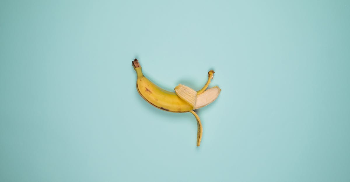 Can you tell how ripe a banana is by the actual fruit not the peel? - Top view backdrop of tasty whole banana with blots on yellow peel and curved stalk