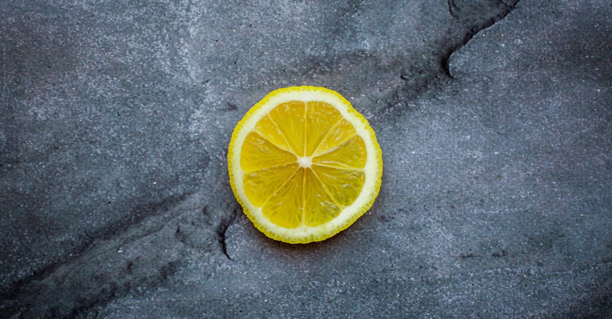 Canned Peppers: Very subtle acidic taste - Top view ripe sour lemon slice placed on dark gray cracked background in studio