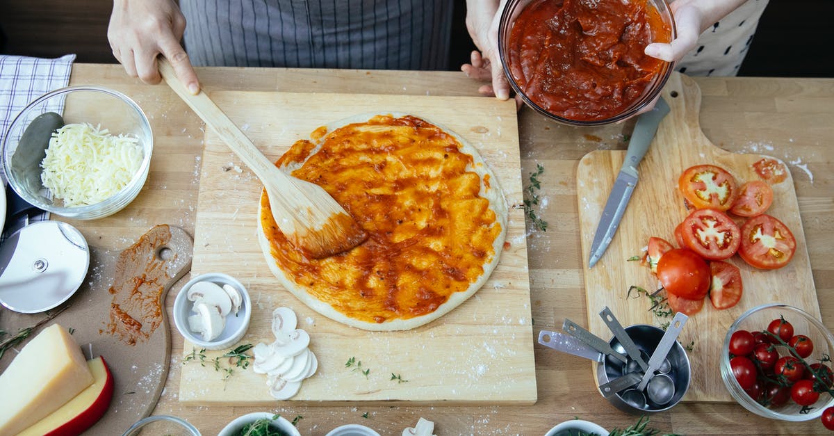 Canning cheese spreads? - Crop women spreading tomato sauce on pizza