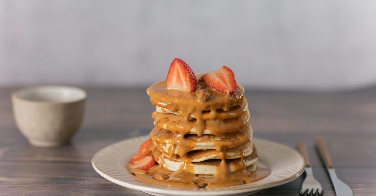 Caramel sauce tastes too sugary what went wrong - Appetizing pancakes topped with ripe strawberries and sweet caramel served on wooden table with cutlery and mug in light kitchen