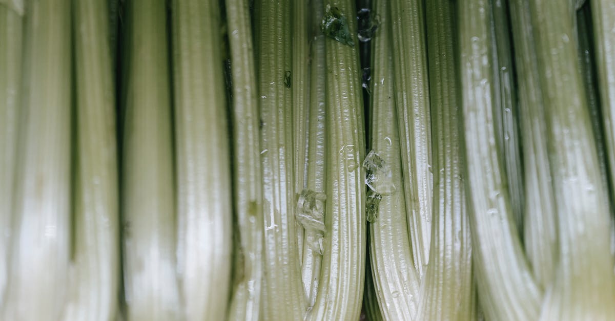 Celeriac (aka: Celery Root) Skin - Edible or Not? - Backdrop of raw celery with wavy leaves and thick green stems in shiny light