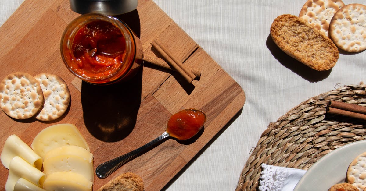 Cellophane lids on jam - Red Sauce in a Glass Jar and on a Spoon on a Wooden Board