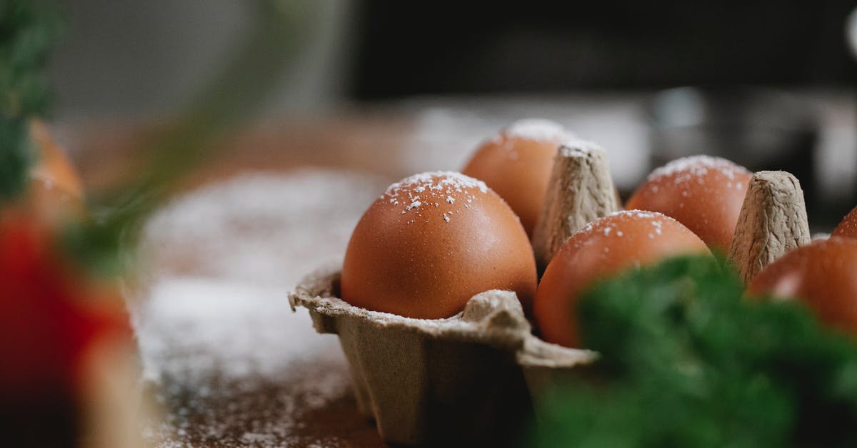 Changing Protein Content of Flour - Uncooked chicken eggs in carton container with fresh greens placed on table with flour