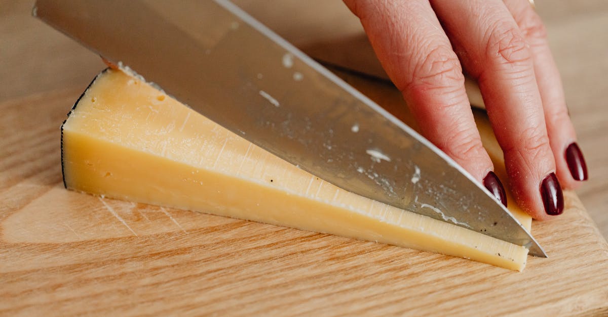 Cheese Cutting Tools - Person Holding Stainless Steel Kitchen Knife Slicing a Cheese