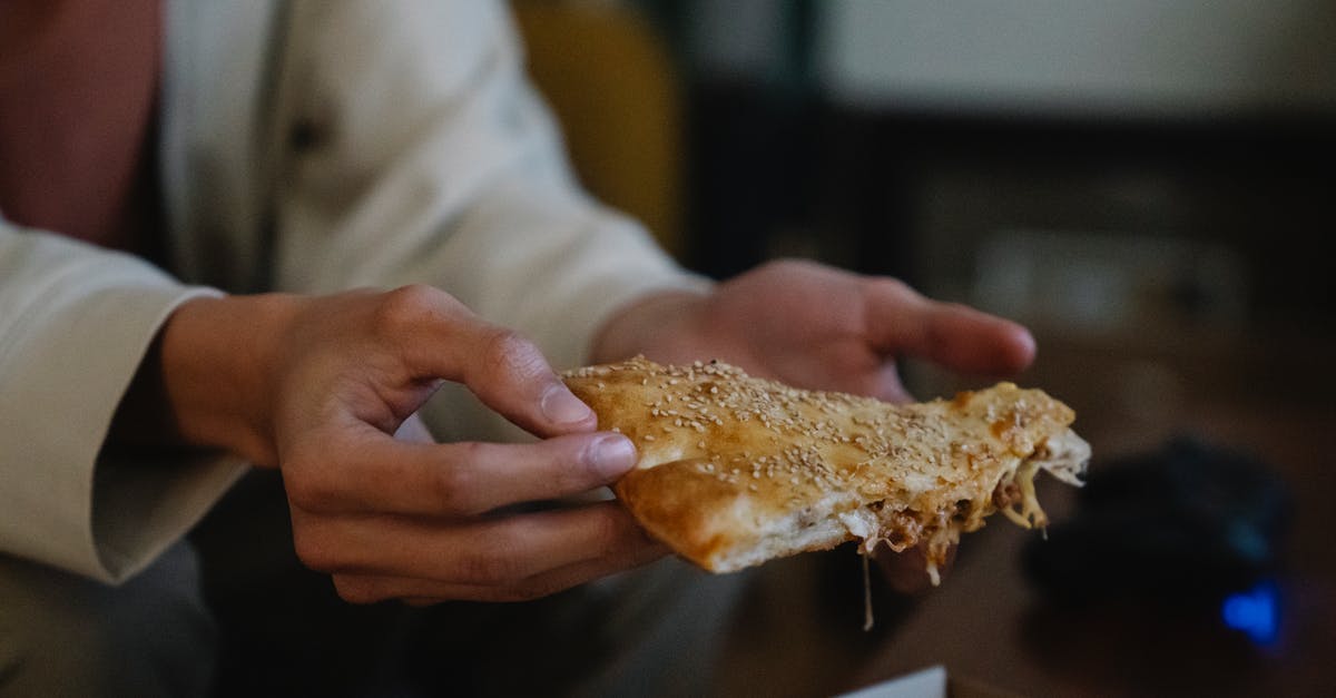 Chemical meat tenderizers - Crop unrecognizable male with tasty pie piece with sesame seeds on top in house room