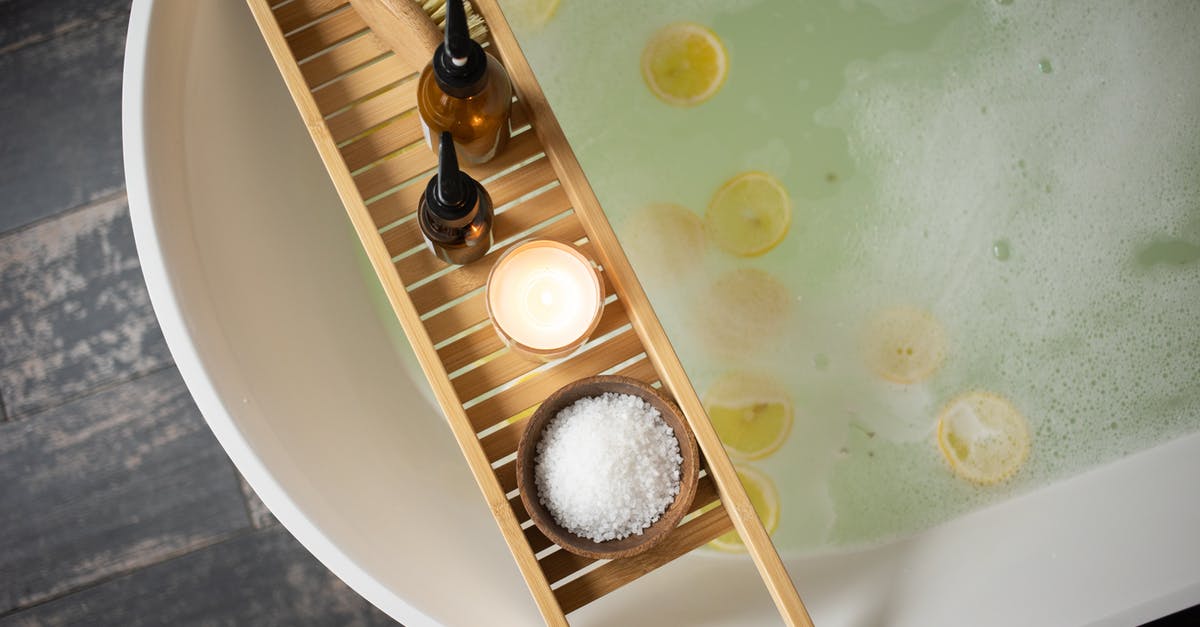 Cherries + 2% salt + 1 week at room temperature =? - Top view of wooden tray with salt and bottles of cosmetic products placed on white tub with lemon slices on water surface