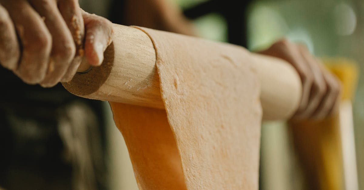 Chewy, Moist & Bit Uncooked Bread - Low angle of unrecognizable person stretching soft dough on rolling pin while preparing food in kitchen