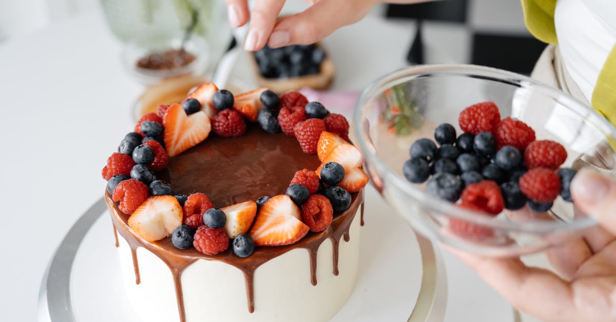 Chocolate Berry Cake with Berries as main batter ingredient? - Female confectioner decorating homemade cake with berries