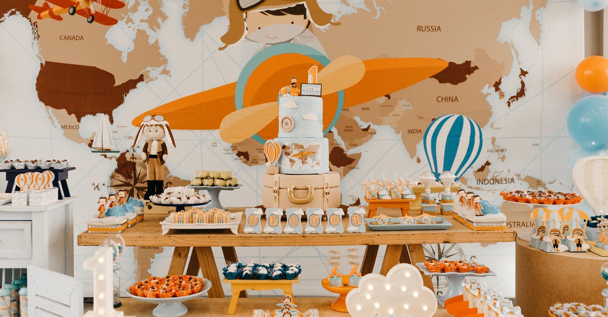 Chocolate layer cake tears easily - Bright colorful decorations in travel theme with cake and various sweets against map