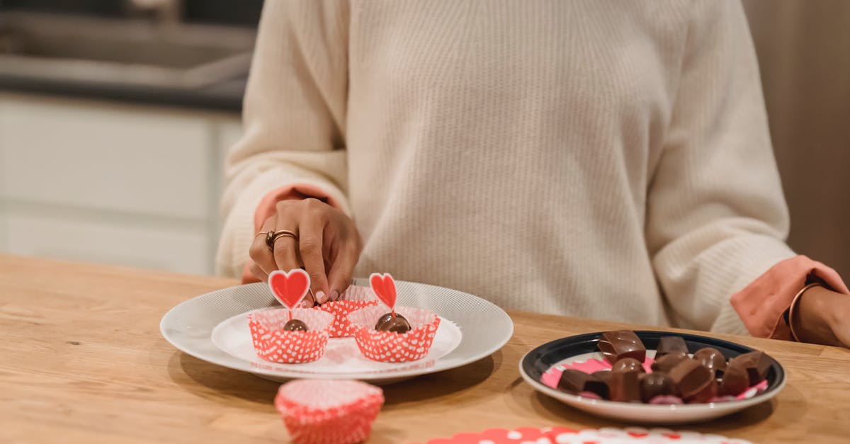 Chocolate molds in shapes of kitchen supplies - Unrecognizable female standing at wooden table with plates of delicious sweet chocolate candies served in molds in kitchen at home