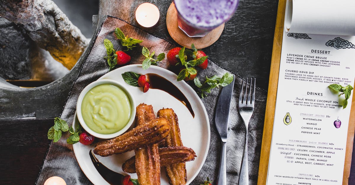 Chocolate pancakes using melted chocolate - From above of delicious Spanish churros with green dip sauce garnished with fresh strawberries and melted chocolate near glass of blueberry milkshake and menu in restaurant