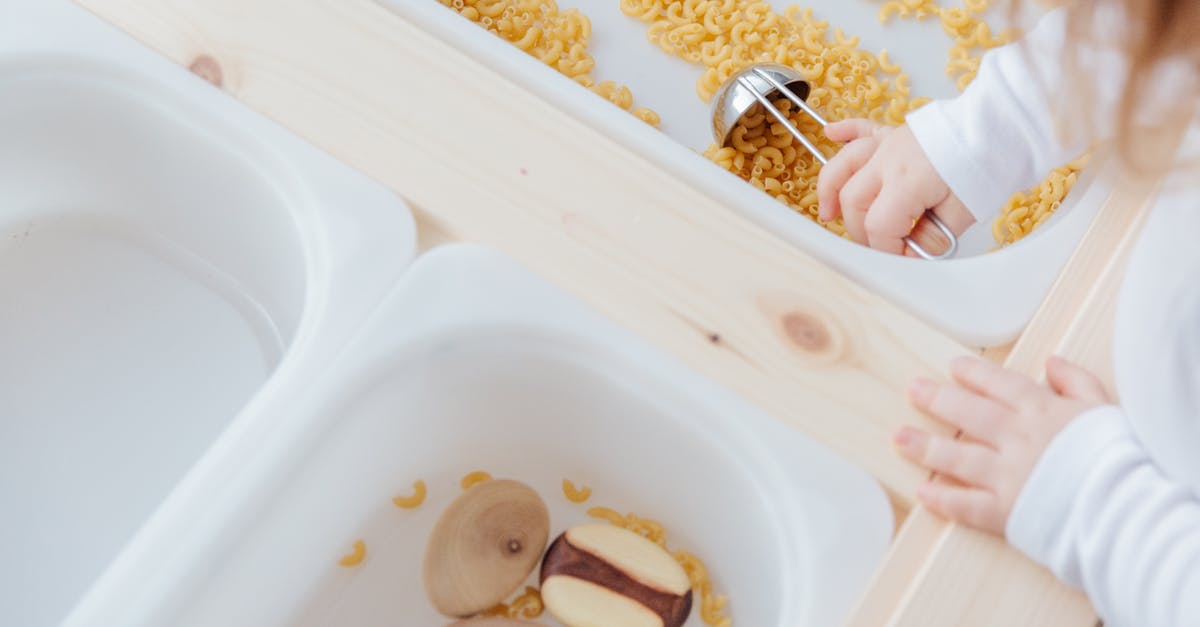 Chopped onions in metal or plastic containers - Little girl collect raw pasta with metal spoon in plastic container