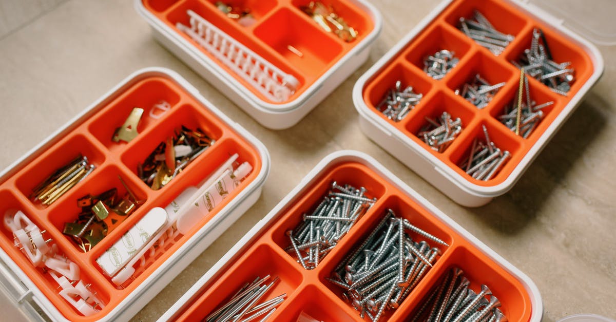 Chopped onions in metal or plastic containers - From above of boxes with different metal nails and plastic dowels in workshop