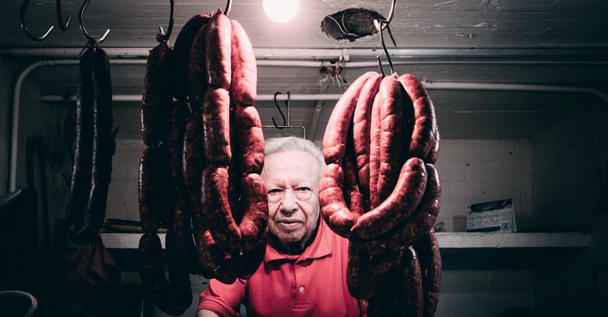 Chorizo sausage as a ground chorizo substitute? - Man in Red Polo Shirt Standing Near Hanging Meat while Seriously Looking at the Camera