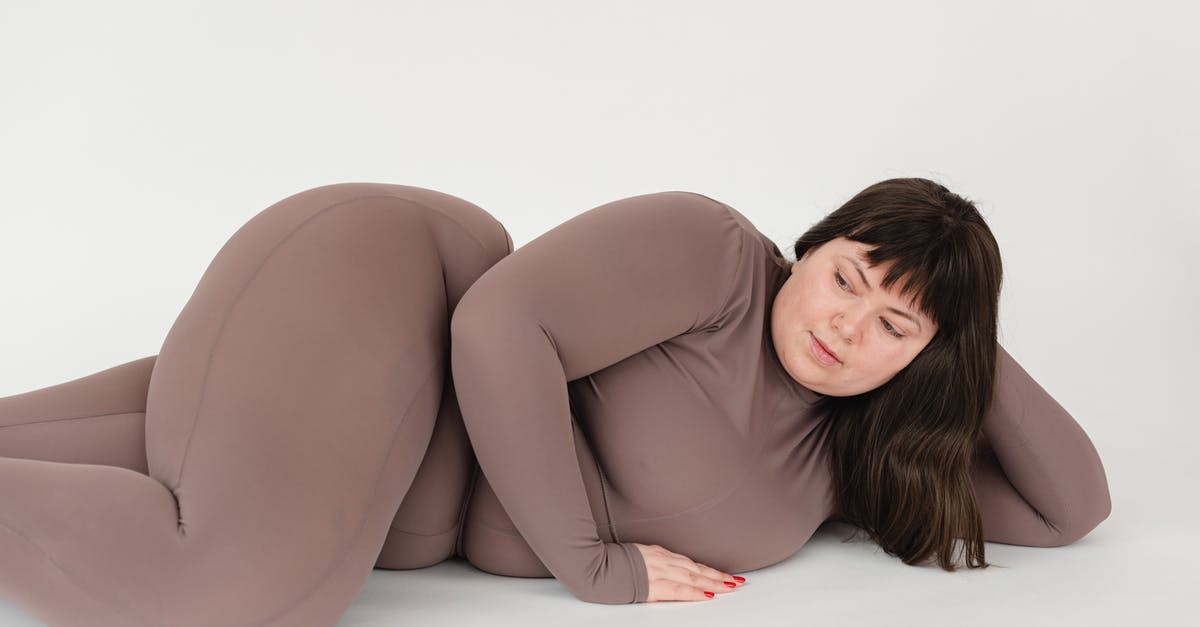 Chunky Peanut Butter - High angle of serious plus size female with long hair leaning on hand while lying against white background