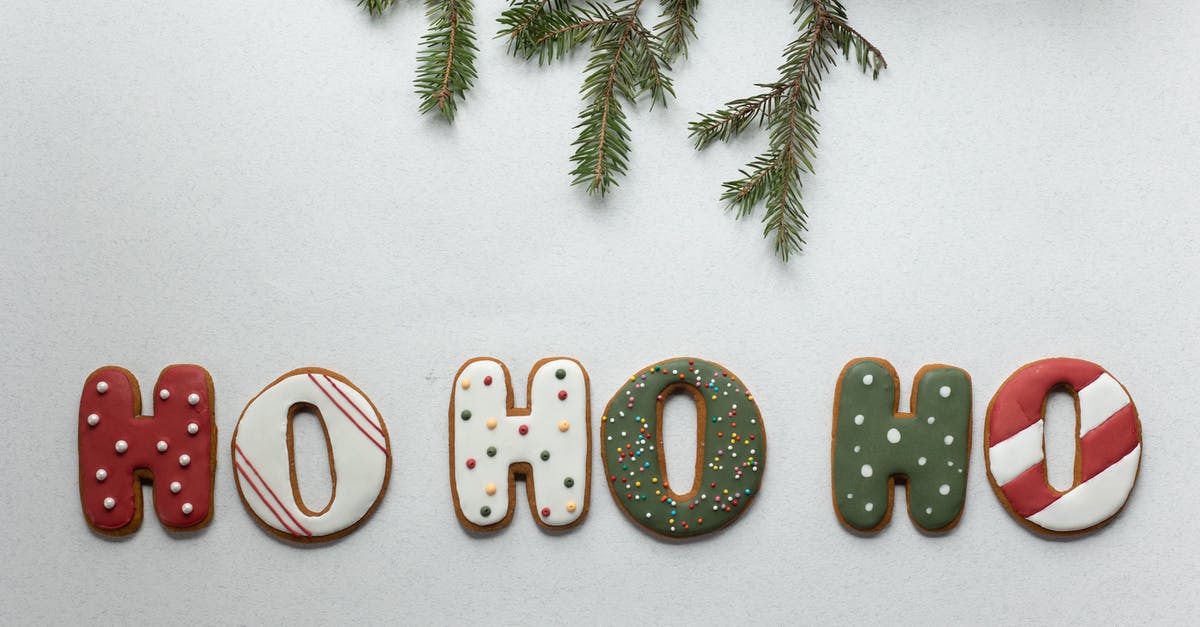 Cinnamon is discoloring my icing - From above of traditional Christmas gingerbread with Ho Ho Ho letters composed with coniferous branch on white background