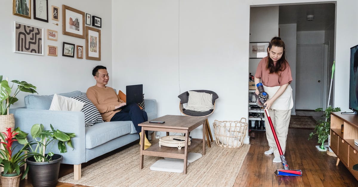 Cleaning a Sieve - A Man Working from Home and a Woman Vacuuming in a Living Room