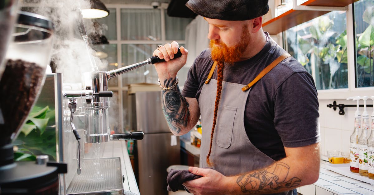 Cleaning burr coffee grinder - Tattooed barista cleaning coffee maker with steam