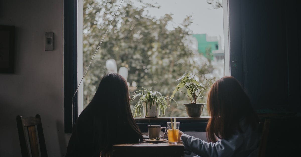 Cleaning out coffee pots and thermoses - Two Women Sitting at Table Near Window