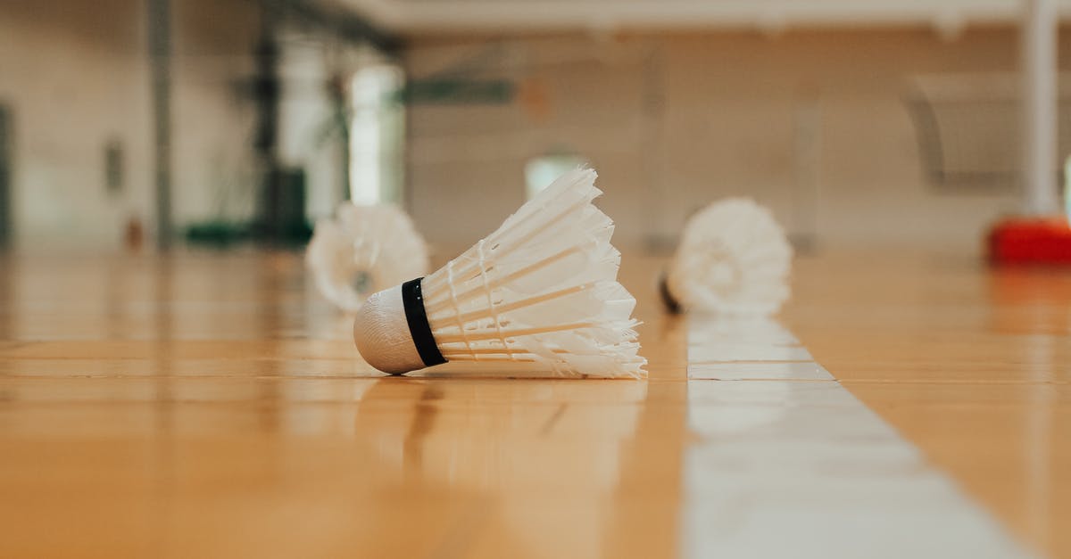 Cleaning out residue from thread of sport mixer base - Ground level of similar plastic shuttlecocks reflecting on bright shiny floor with marking line