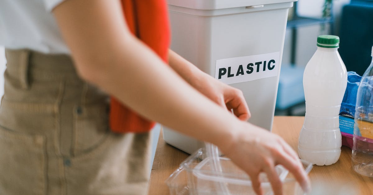 Cleaning plastic bags used for sous vide - Crop anonymous female in casual clothes standing near bucket for plastic and sorting out rubbish in light room