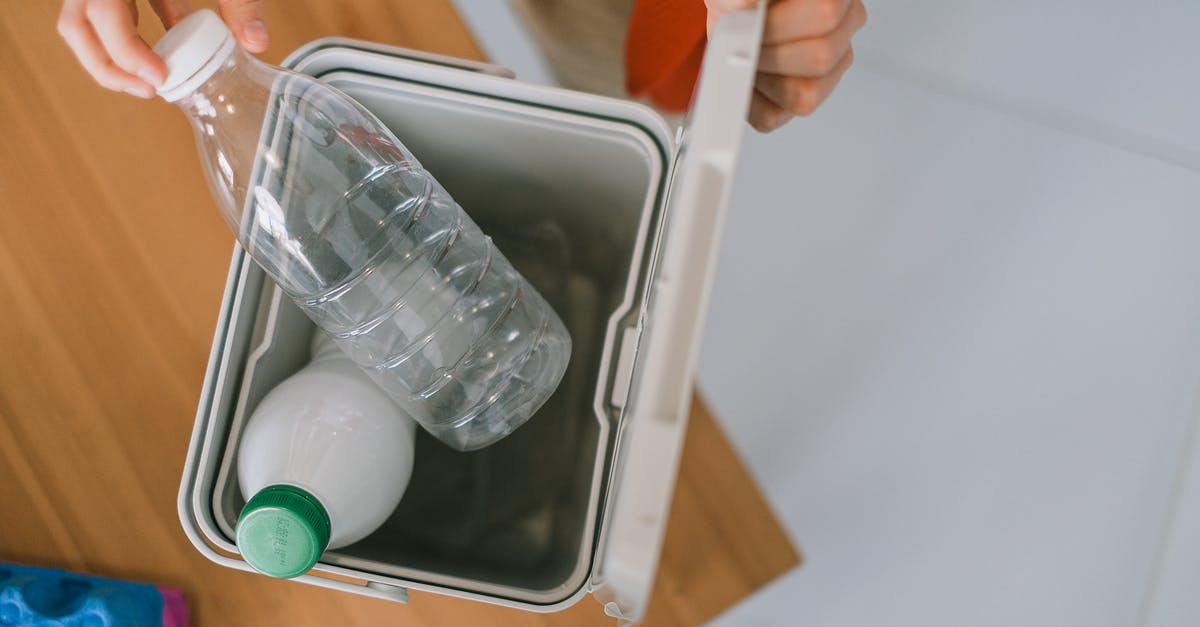 Cleaning plastic bags used for sous vide - Top view of crop anonymous person opening container while disposing plastics bottle on wooden table