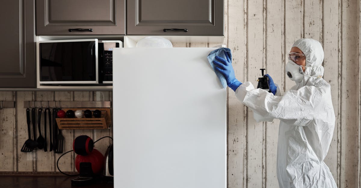 Cleaning tin discoloration on copper/tin lid - Person in Protective Suit Disinfecting A Refrigerator