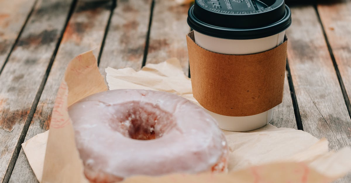 Closest thing to a donut I can drink coffee out of - Tasty sweet chocolate donut and takeaway cup of coffee placed on wooden surface in daytime