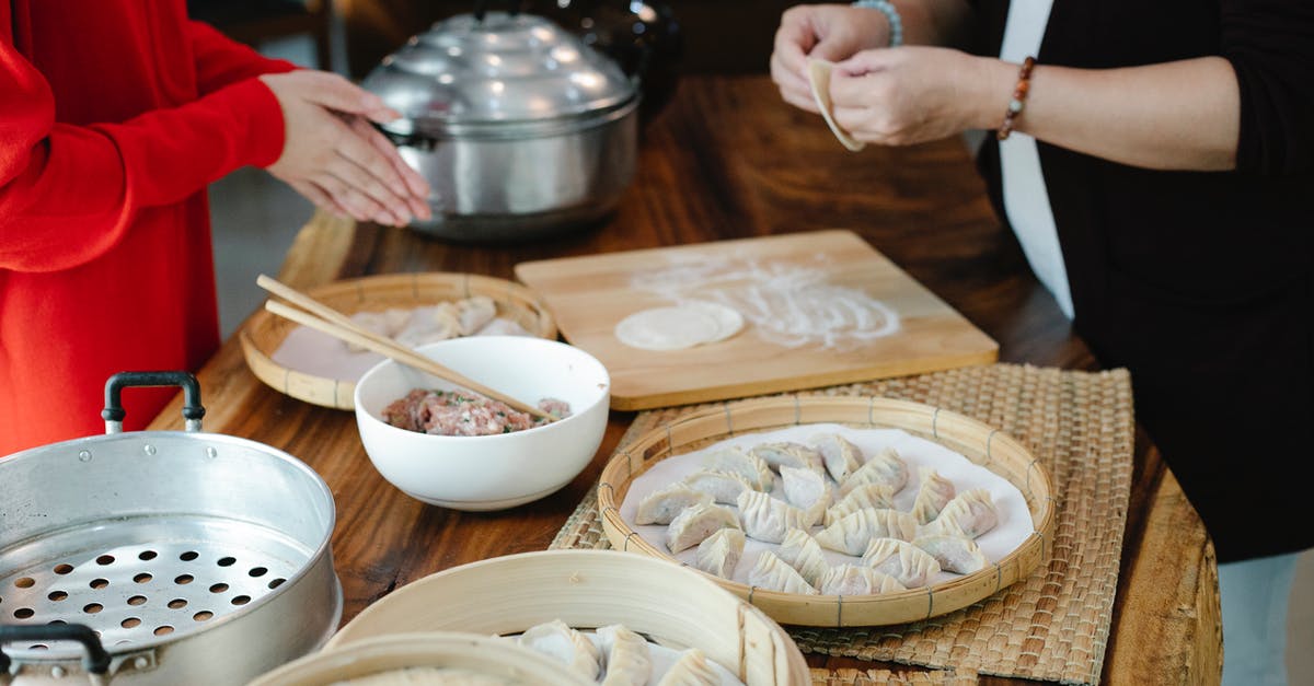 Coating meat in flour before browning, bad idea? - Side view of crop anonymous female relatives cooking dumplings with minced meat filling at kitchen table