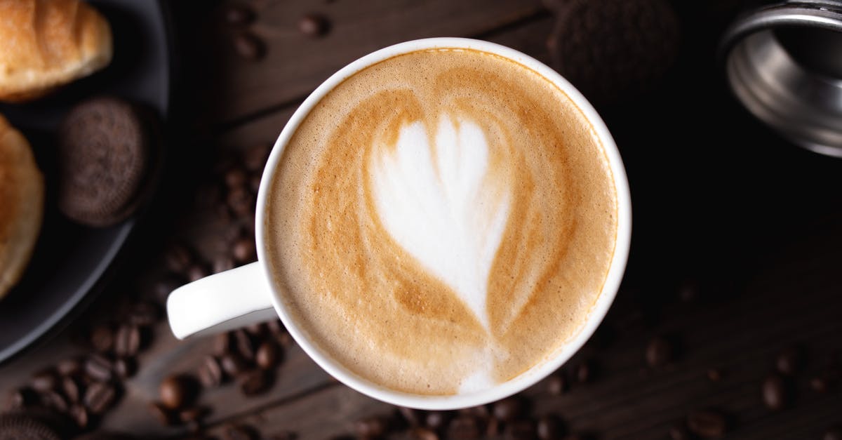 Coffee flavored melted chocolate for drizzling over cookies? - Top view composition of freshly brewed cappuccino served on dark table and surrounded by coffee beans and chocolate cookies