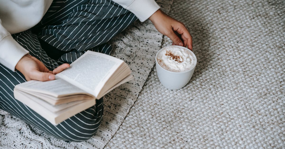 Coffee whipped cream filling - From above of crop anonymous female sitting with crossed legs and reading book with mug of coffee with whipped cream while resting at home