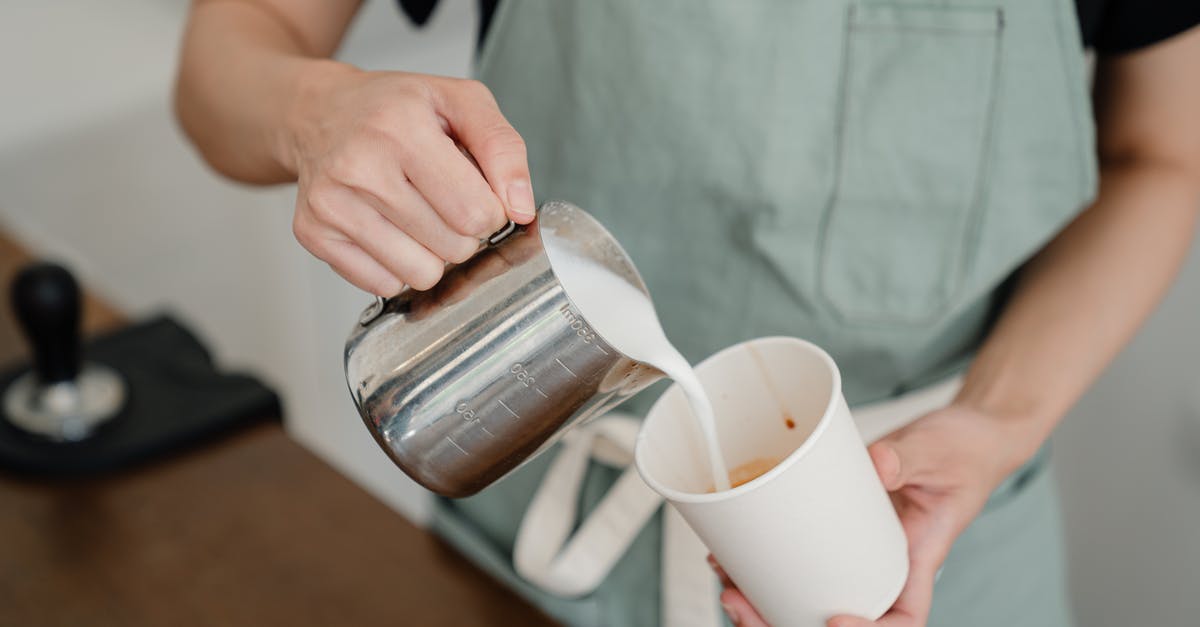 Coffee whipped cream filling - Anonymous barista pouring milk from jug into paper cup