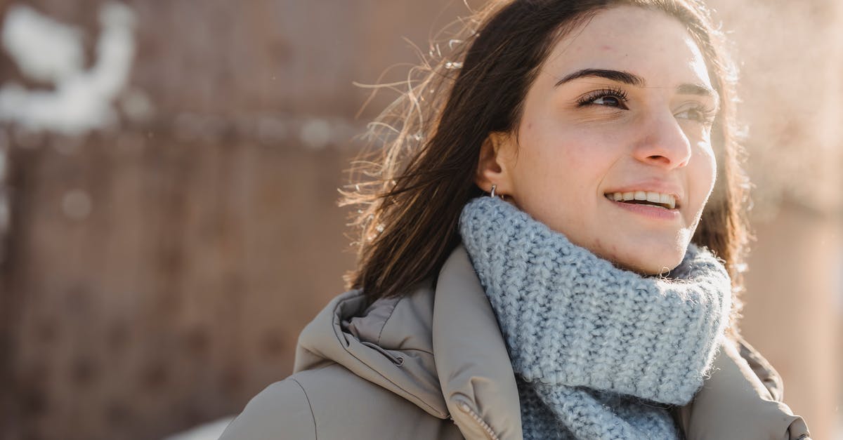 Cold Smoking in the Tropics - Condensation - Content young brunette in blue sweater and warm jacket standing on snowy city street on cold sunny day and looking away