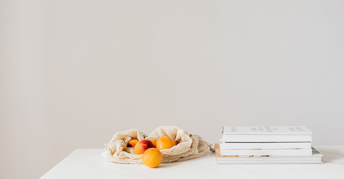 Collecting acorns to eat - how/when? - Jute sack with natural ripe apricots on white table composed with stack of various books and magazines