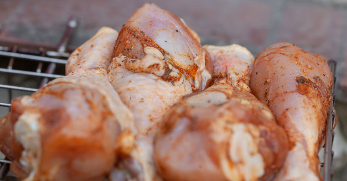 Confusion about chicken leg & thighs nutrition facts (calories) - From above of raw chicken legs with seasoning placed on metal grill grate in daylight