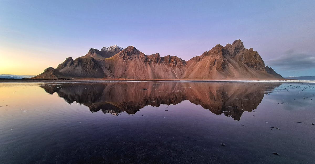 Considerations for frying a Turkey in Arctic Weather - Island with high rocky brown mountains surrounded by lake with crystal clear blue water and melting ice in twilight