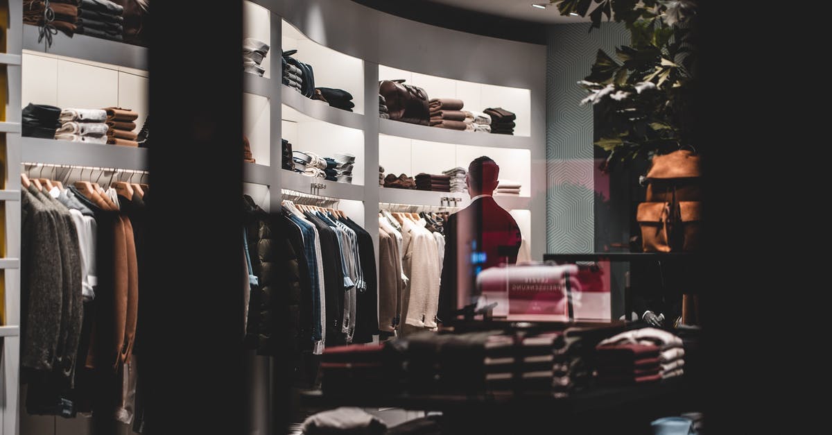 Consuming cardamom pods - Back view of faceless elegant male customer in suit choosing new clothes while standing near wardrobe in modern fashion boutique