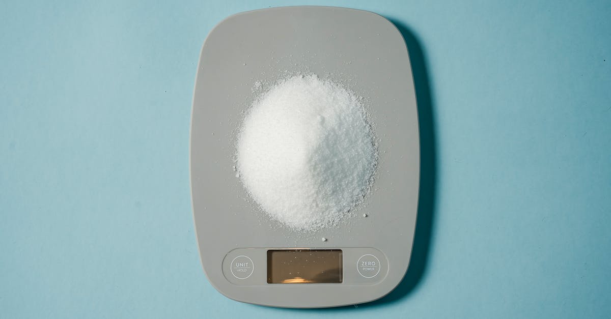 Convert weight of Confectioners sugar to caster sugar - Top view of kitchen scales with electronic display measuring weight of sugar on blue background