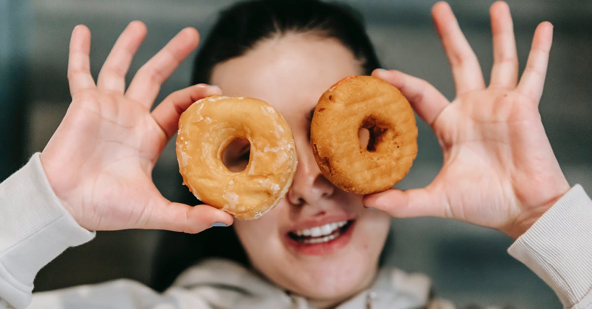 Convert weight of Confectioners sugar to caster sugar - Positive young female in casual clothes smiling while covering eyes with delicious doughnuts