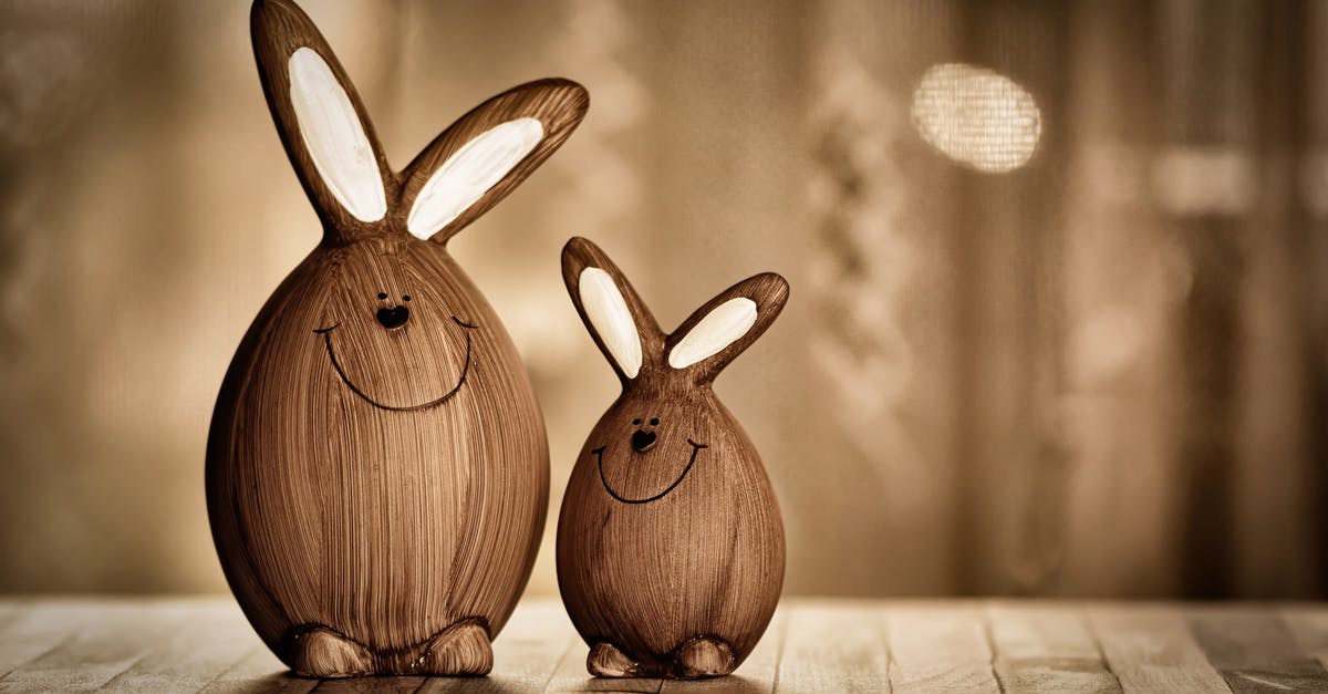 Converting between Egg sizes - Wooden eggs in form of rabbits with big ears and lines with dots representing muzzle placed on table in room with artificial light during Easter holiday