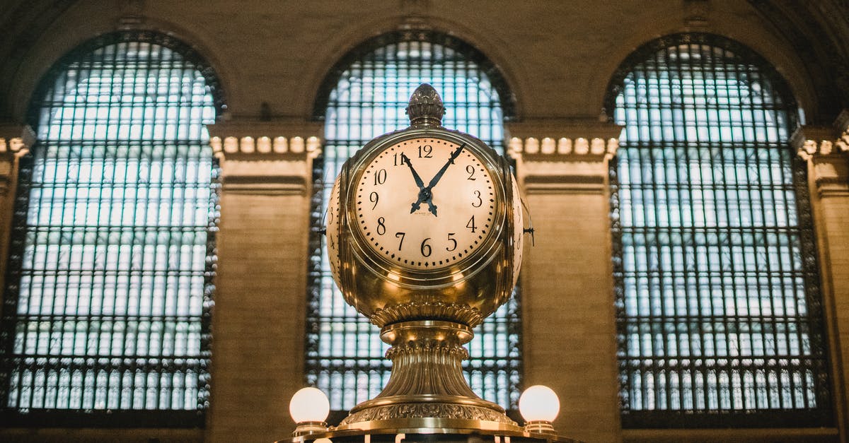 Converting oven time and temp from convection to conventional - From below of aged retro golden clock placed atop information booth of historic Grand Central Terminal with arched windows