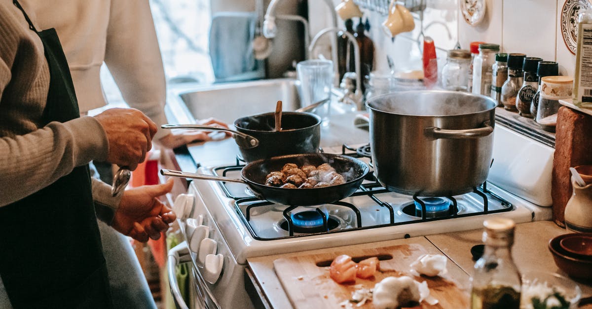 Cook lentils before or after shaping into veggie meatballs? - Anonymous man frying meatballs standing in kitchen with wife