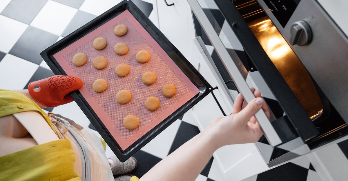 Cook steak in oven with tray meant for deserts? - From above of crop unrecognizable female opening oven and putting baking pan with uncooked cookies inside oven in kitchen