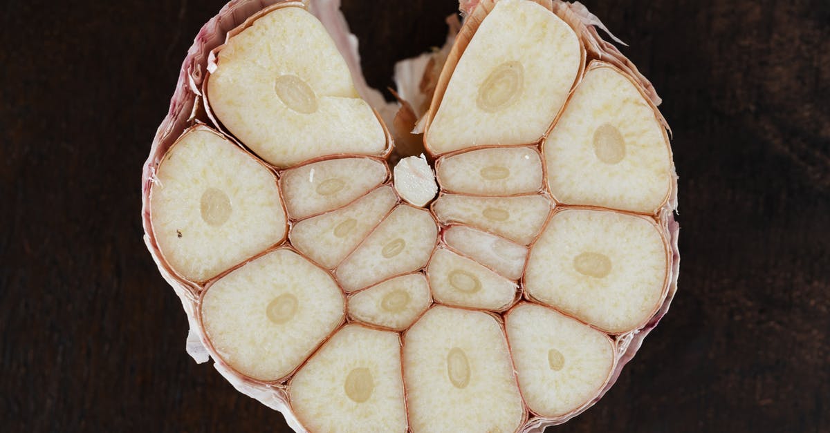 Cooked or Raw - Shrimp peeling - Bulb of ripe garlic in peel cut in half on wooden board