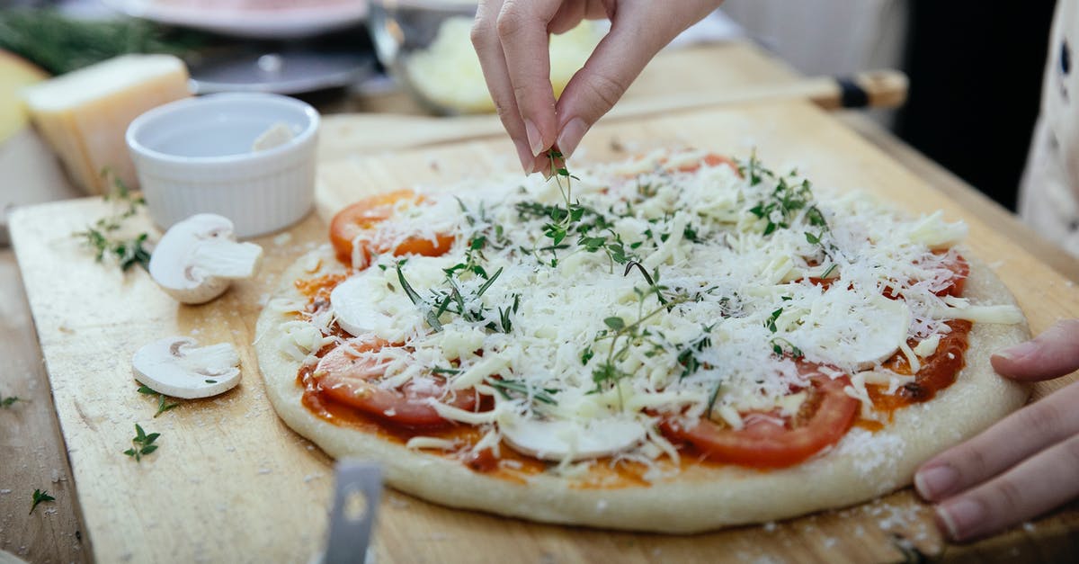 Cooked or raw mushrooms on pizza? - Crop woman adding herbs on pizza