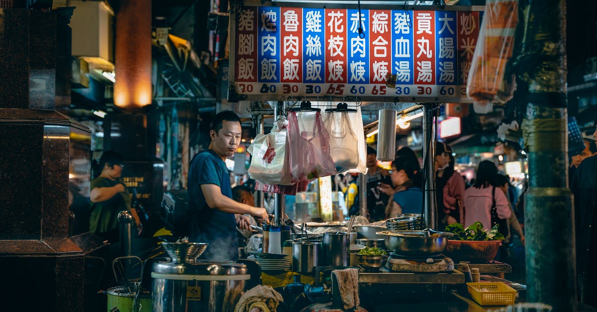 cooking in a plastic bag without removing extra air, at 100c? - Side view of thoughtful male cook looking down while preparing food at table with bowls under colorful signboard with hieroglyphic inscriptions and numbers near customers at night