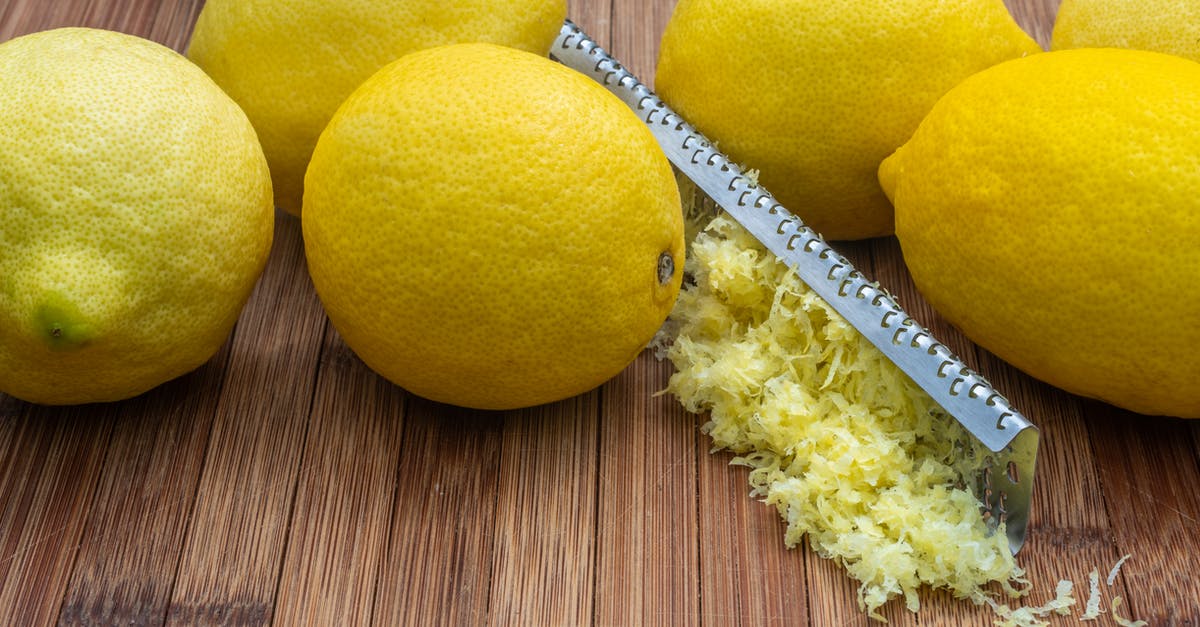 Cooking lemon juice into stew - High angle of fresh ripe lemons and zest placed near grater on wooden table