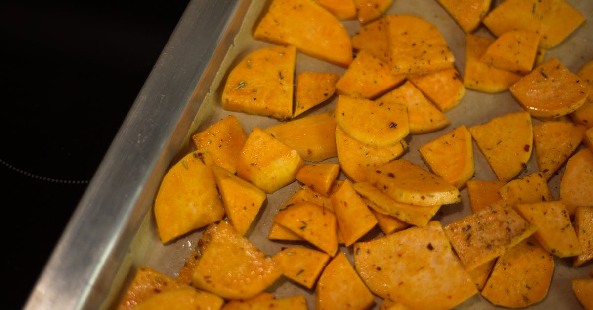 Cooking liquid in oven turns crispy skin soggy - From above of appetizing sliced fried potatoes with spices scattered on oven pan in kitchen