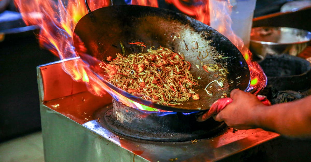 Cooking meat directly above the flame of a gas stove - Person Cooking Noodles