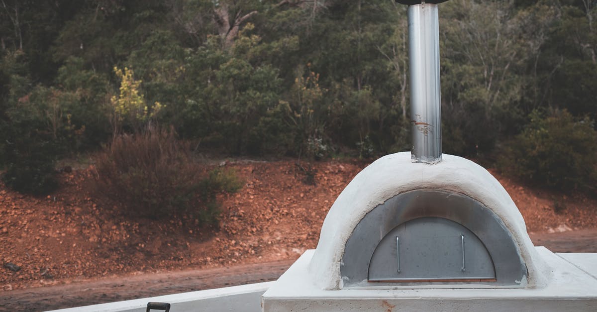 cooking oven temperature - Stone pizza oven with stainless flue placed in lush summer garden for picnic